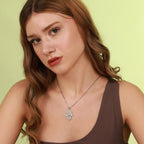 Woman wearing a polished sterling silver necklace with a hamsa hand pendant against a light green background