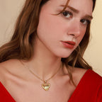 Woman wearing a gold necklace with a heart pendant against a beige background