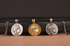 Three coin-shaped pendants on chains against a dark background