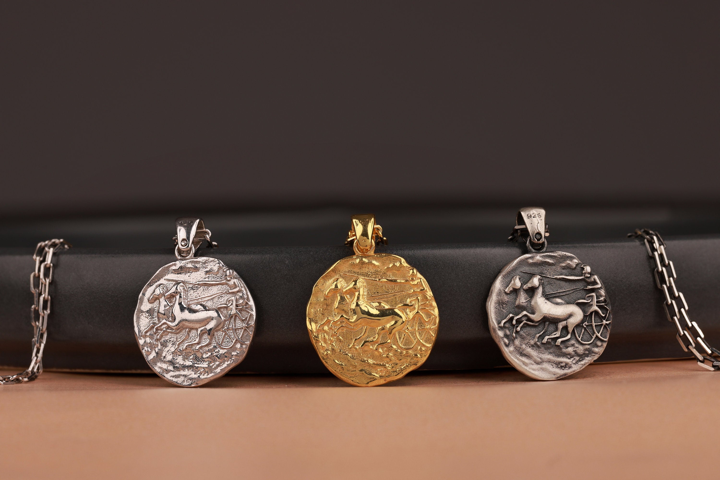 Four pendants on chains against a dark background