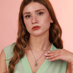 A woman wearing a swan necklace with a pink background