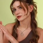 Woman wearing a necklace with a green background