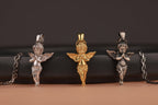 Three sculptural angel-shaped pendants on chains against a dark background