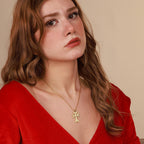 Woman wearing a gold vermeil necklace with an Armenian khachkar  cross pendant against a beige background