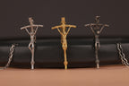 Three crucifixes in gold, silver, and oxidized on a black background