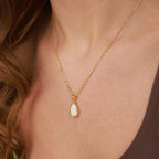 Gold necklace with a teardrop-shaped pendant on a person's neck