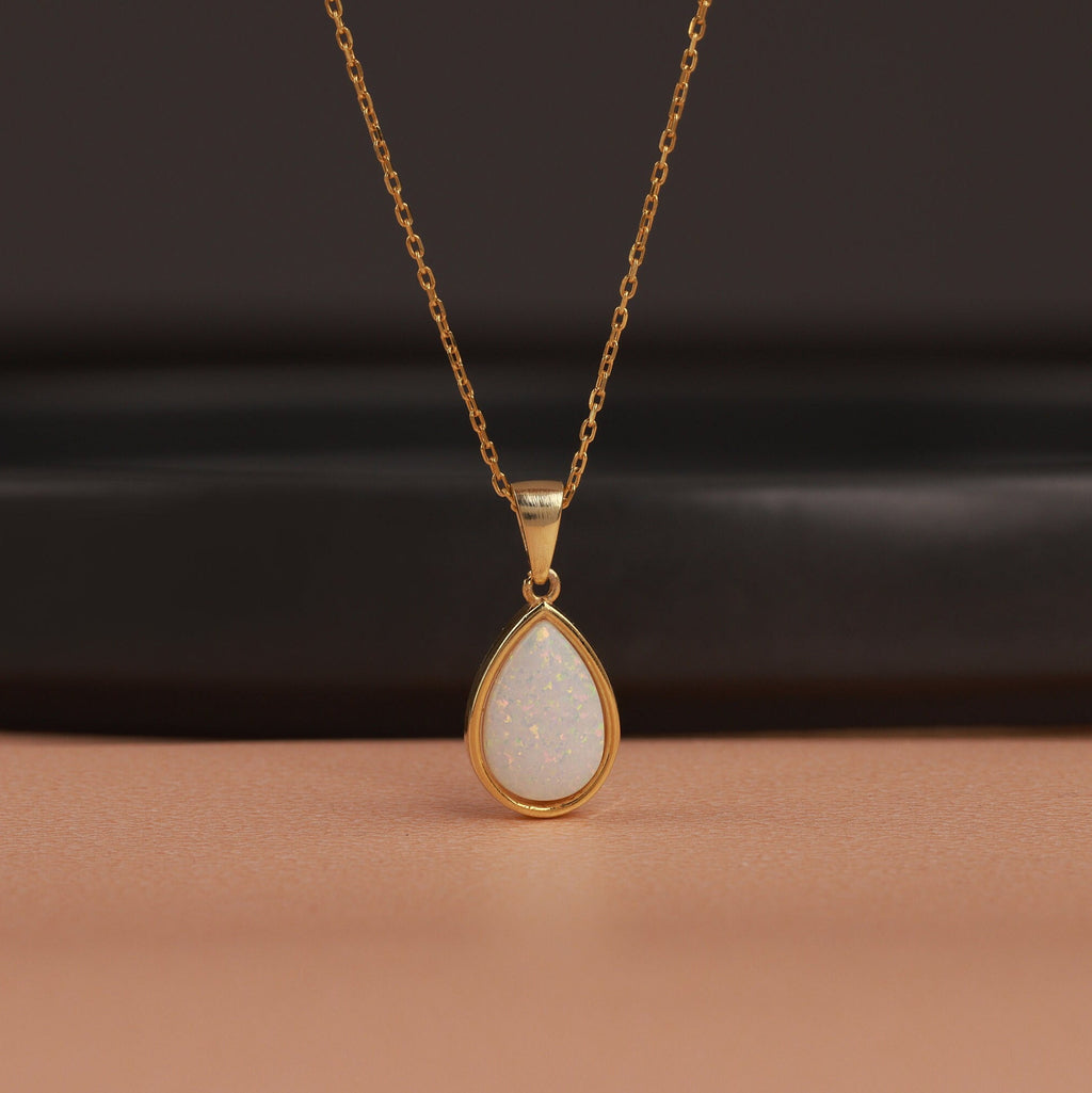 Gold necklace with a teardrop-shaped pendant on a brown surface