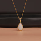 Gold necklace with a teardrop-shaped pendant on a brown surface