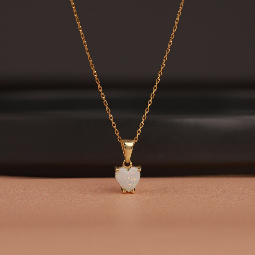 Gold necklace with a heart-shaped opal pendant on a brown background