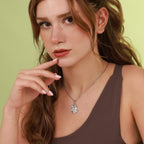 Woman wearing a silver necklace with a pendant against a green background