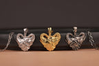 Three heart-shaped elephant family pendants in silver, gold, and oxidized on a dark background