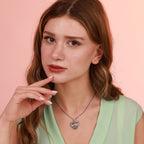 Woman wearing an elephant heart necklace with a pink background