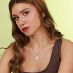 Woman wearing a polished sterling silver necklace with a tree of life pendant against a light green background