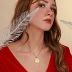 Woman wearing a gold tree of life necklace with a red dress against a beige background