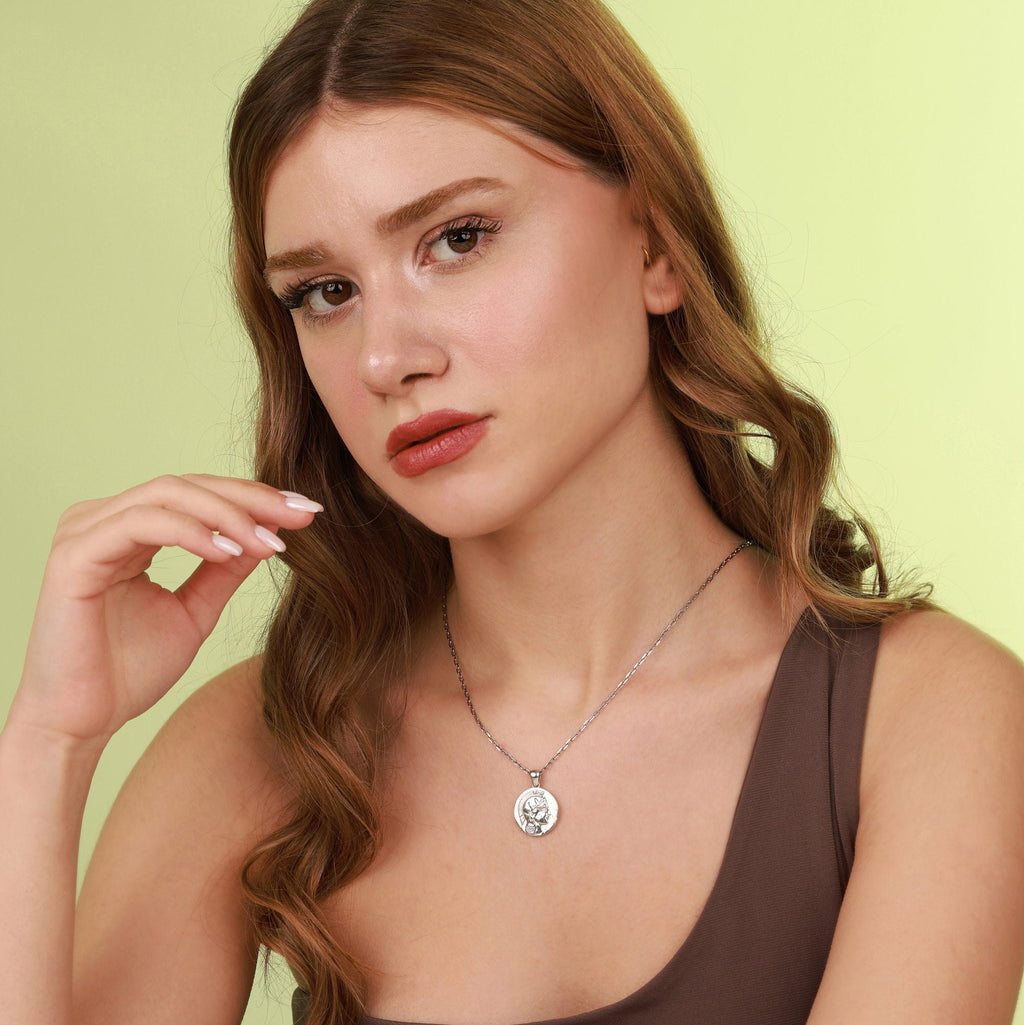 Woman wearing a polished necklace with a pendant against a light green background