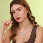 Woman wearing a polished necklace with a pendant against a light green background