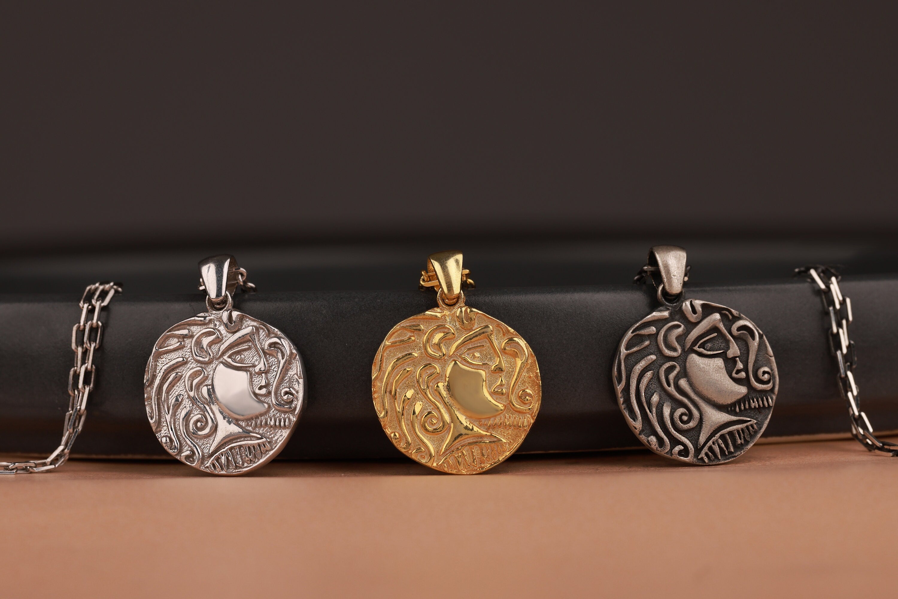 Four ancient silver and gold pendants on a dark surface