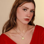 Woman wearing a gold necklace with a pendant against a beige background