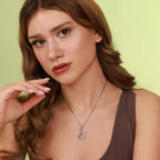 Woman wearing a necklace with a swan pendant against a light green background