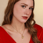 Woman wearing a gold necklace with a swan pendant against a beige background