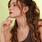 Woman wearing a polished silver necklace with an angel pendant against a light green background