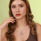 Woman wearing a polished silver vitruvian man necklace with a green background