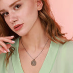 Close-up of a woman wearing an oxidized silver north star necklace with a pink background