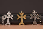 Three Armenian cross-shaped pendants on a dark background