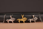 Three lion-themed pendants on chains against a dark background