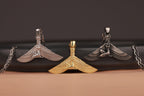 Three-winged isis pendant necklaces on a black and brown gradient background