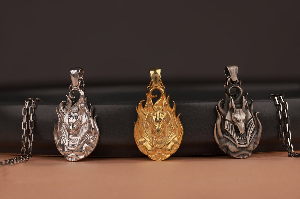 Three anubis-themed pendants on a dark background