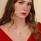 Woman wearing a gold anubis necklace with a pendant against a beige background