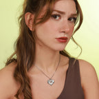 Woman wearing a necklace with a heart-shaped pendant against a light yellow background