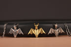 Three bat-shaped pendants on a black and brown background