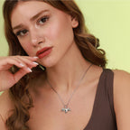 Woman wearing a silver necklace with a polished bat pendant against a light green background