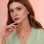 A woman wearing a green top and an oxidized butterfly necklace in sterling silver with a pink background