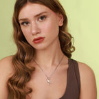 Woman wearing a necklace with a bird pendant against a light green background
