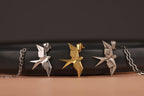 Three bird-shaped pendants on chains against a dark background