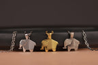 Three elephant-shaped pendants on chains against a dark background