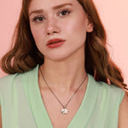 Woman wearing a necklace with an oxidized sterling silver elephant pendant against a pink background