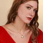 Woman wearing a gold necklace with an origami pendant against a beige background