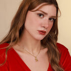 Woman wearing a gold necklace with a rabbit pendant against a beige background