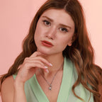 Woman wearing a green top and a flamingo necklace with a pink background