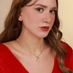 Woman wearing a gold necklace with a flamingo pendant against a beige background
