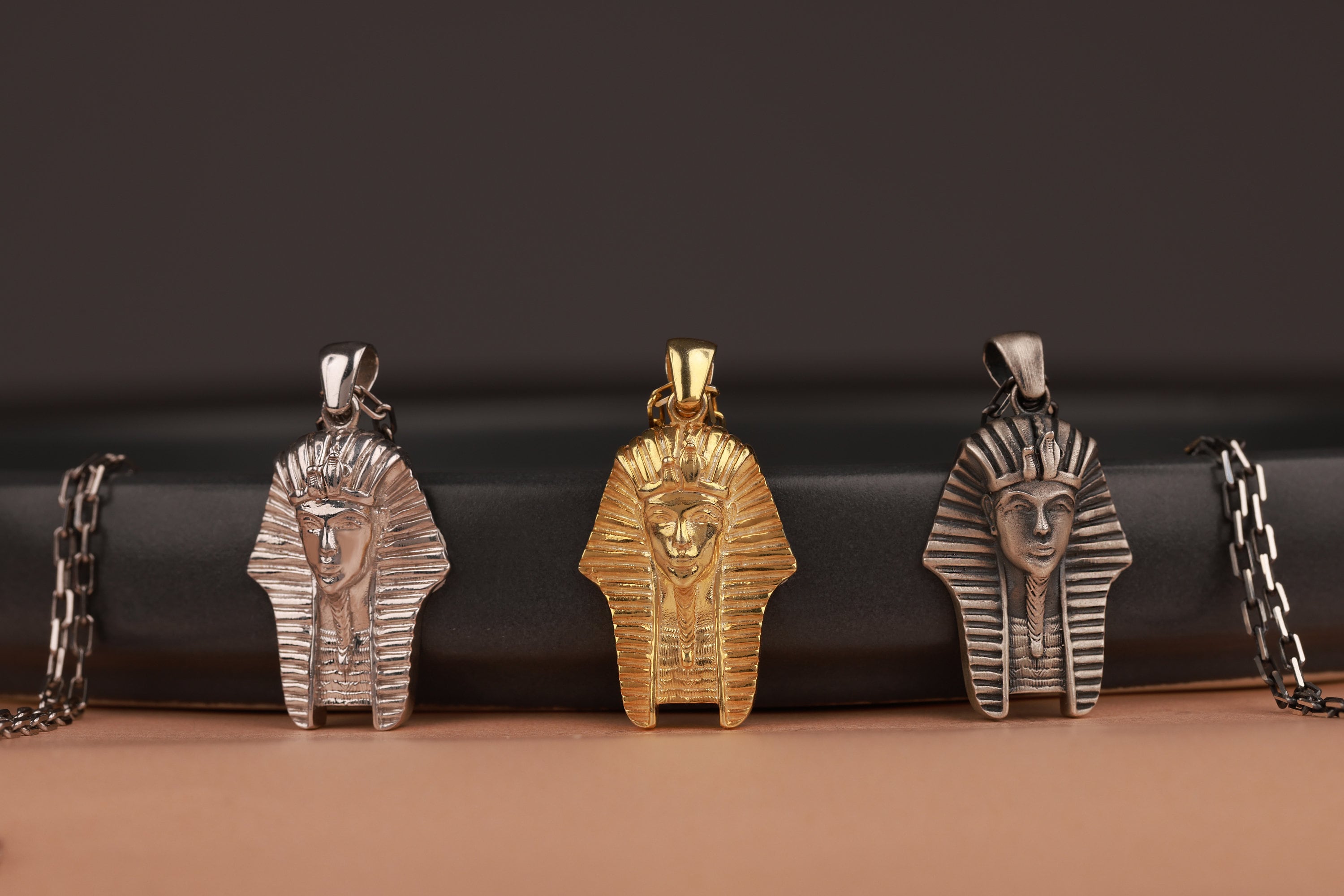 Three Egyptian-themed pendants on a dark background