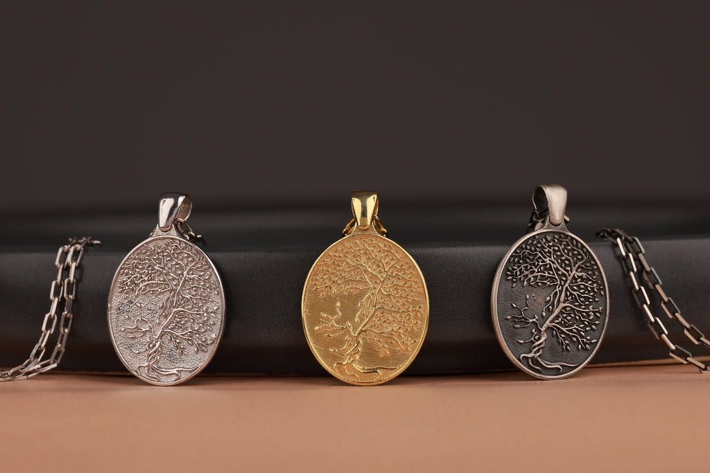 Three tree of life themed pendants on a black and brown background
