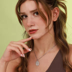 Woman wearing a polished necklace with a tree of life pendant against a light green background