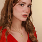 Woman wearing a gold necklace with a horse coin pendant against a beige background