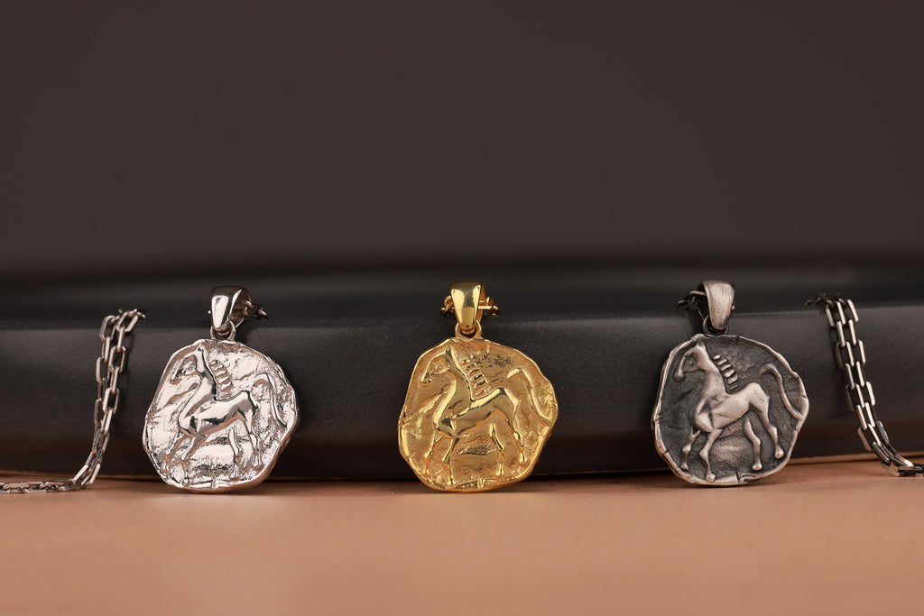 Three animal-themed coin pendants on chains against a dark background