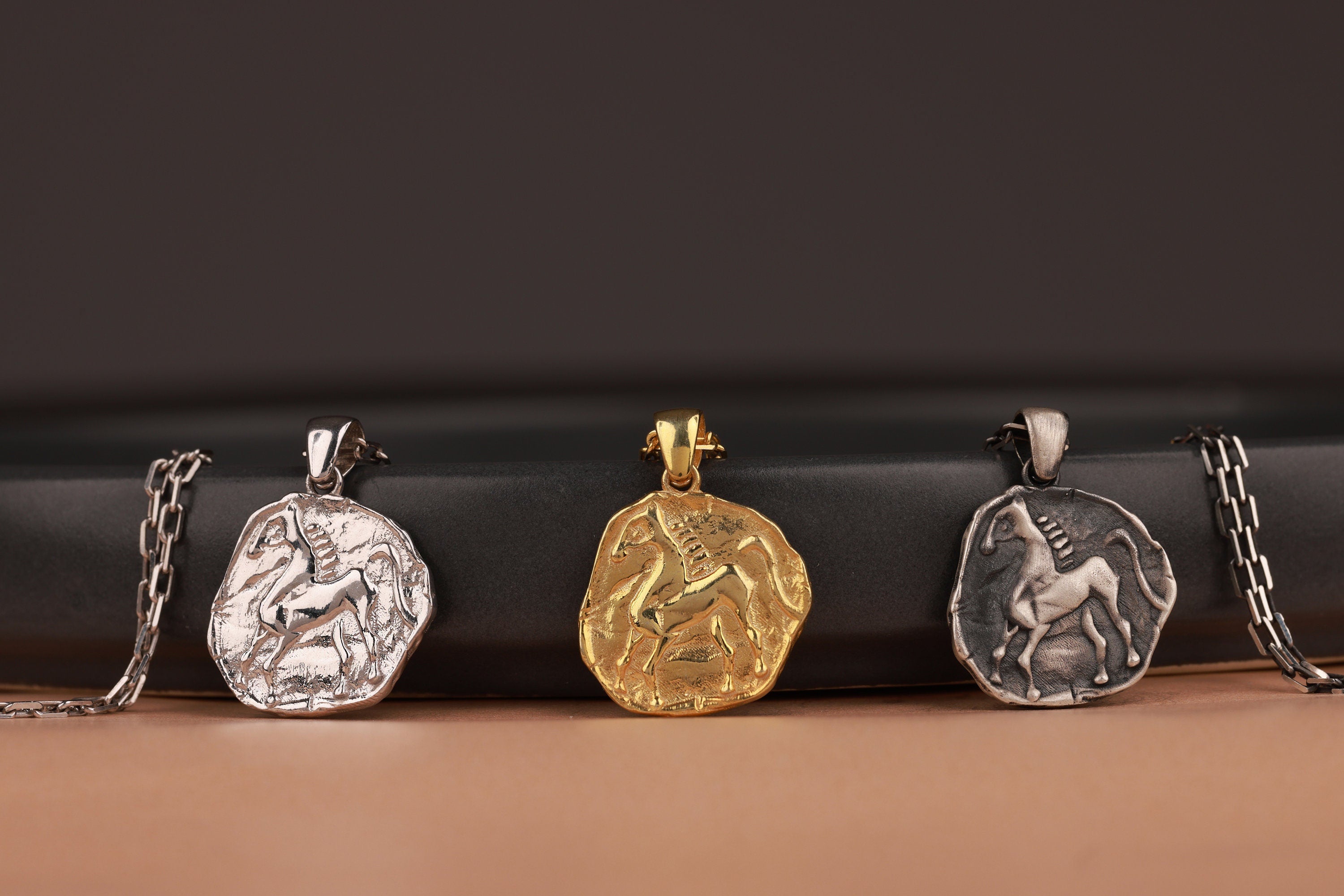 Three animal-themed coin pendants on chains against a dark background